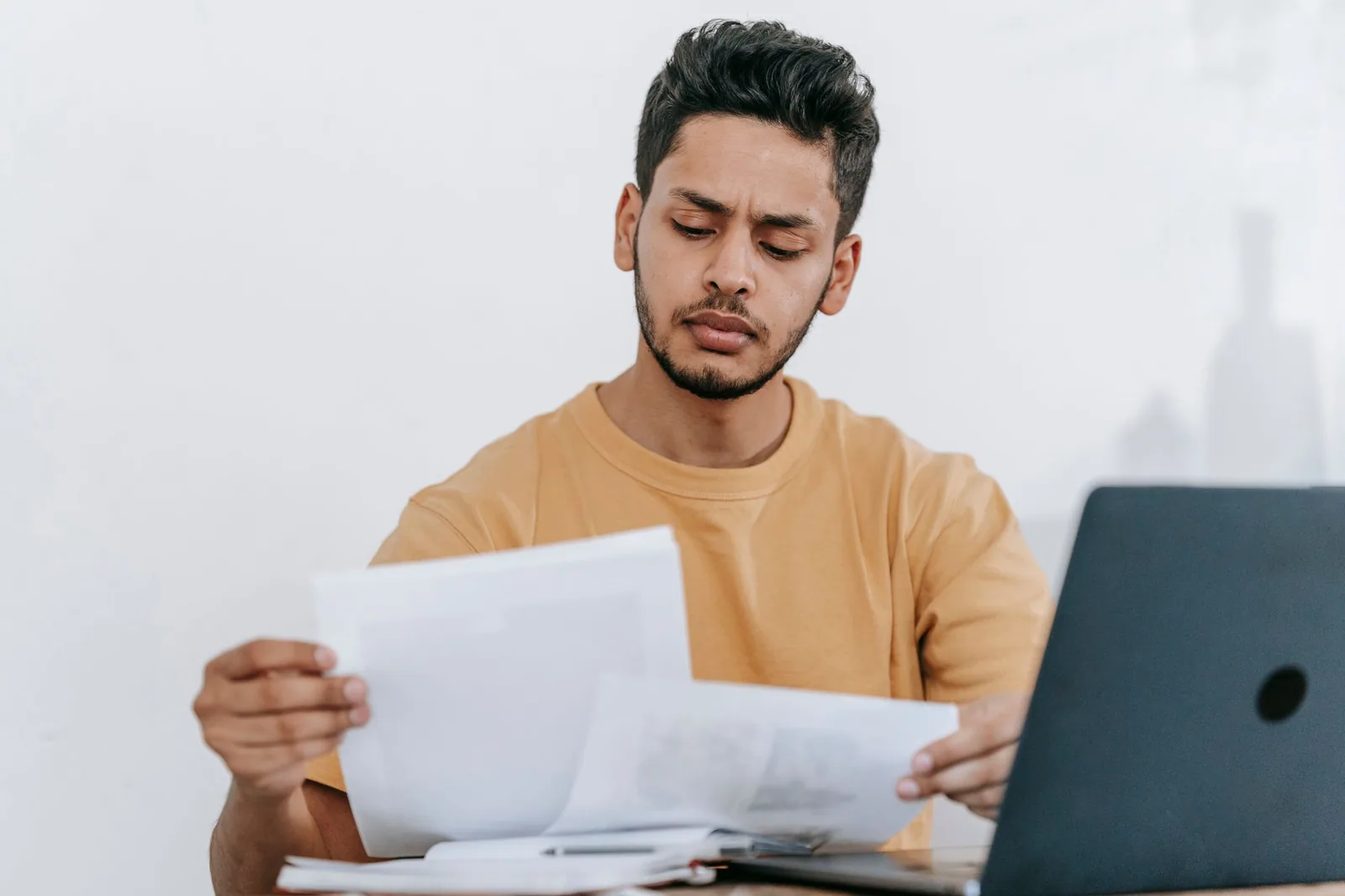 A professional reviewing paperwork beside a laptop