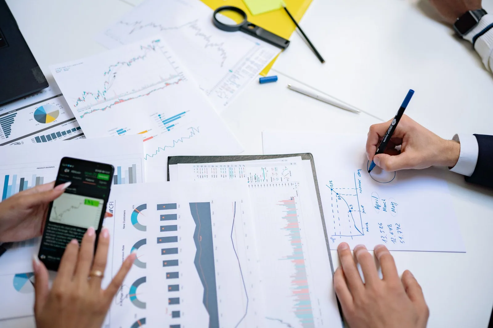 Hands reviewing digital and paper financial records