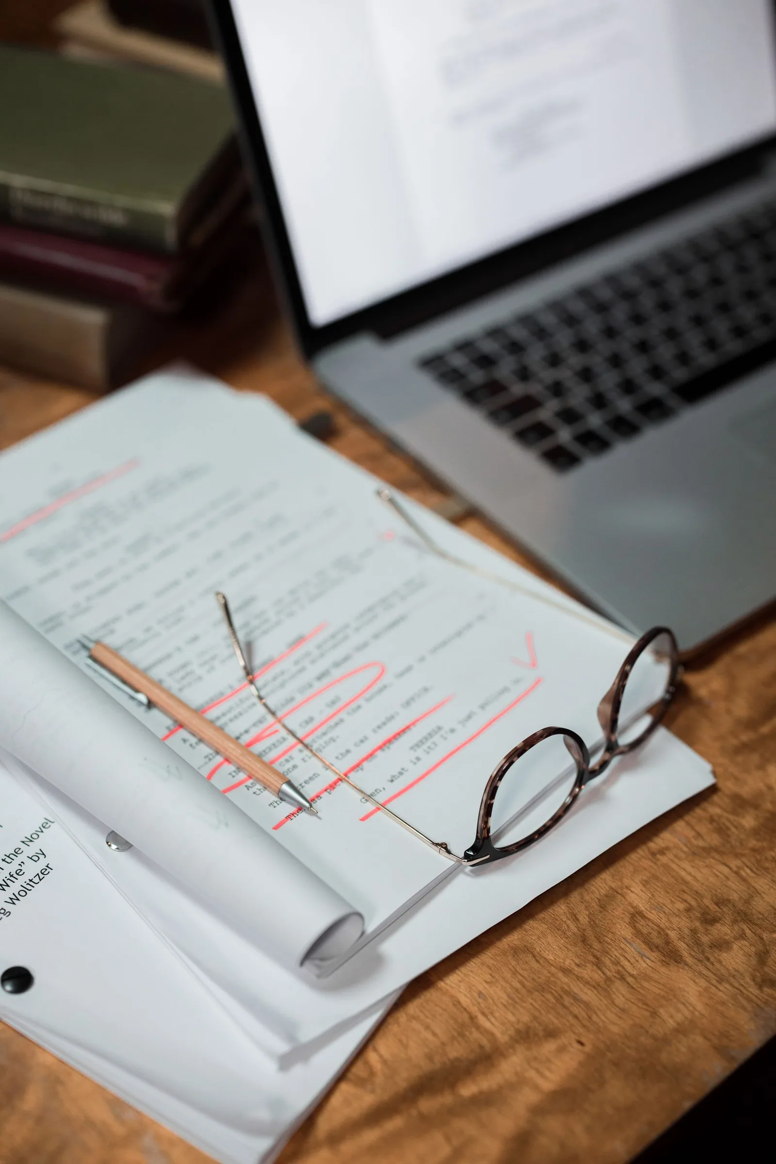 Eyeglasses, paperwork and laptop at a working desk