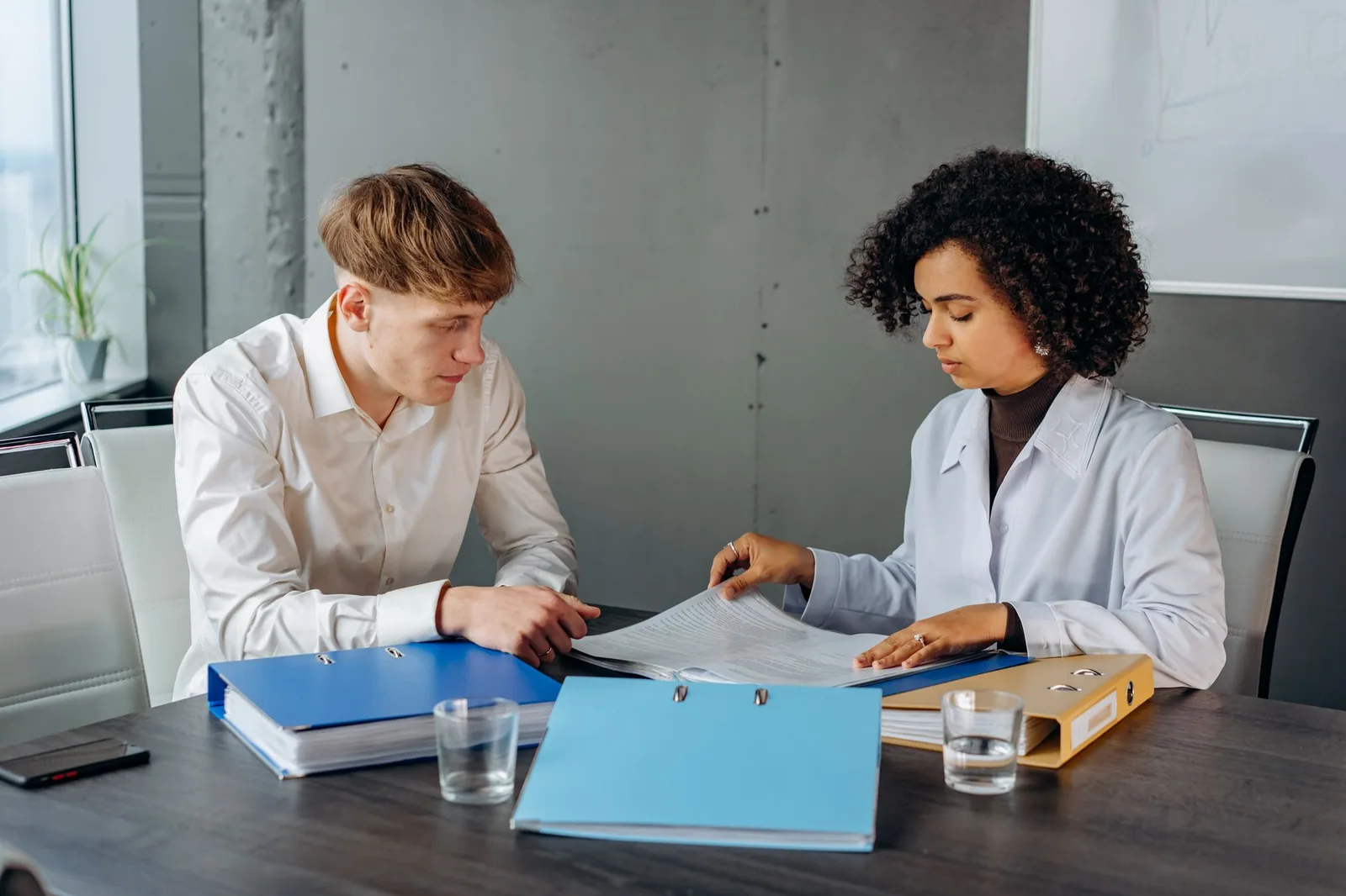 Two coworkers reviewing an office file